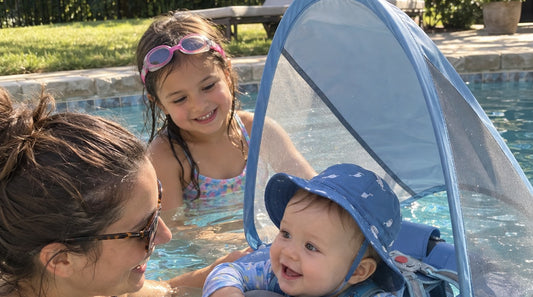 Mamá junto a su bebé en un flotador de pecho con sombrilla y su hija mayor, los tres en la piscina